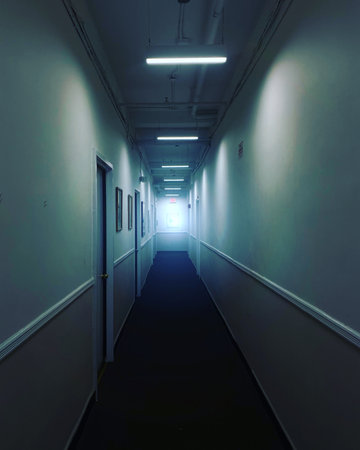 Dark corridor in a hospital with light coming out of the end.の写真素材
