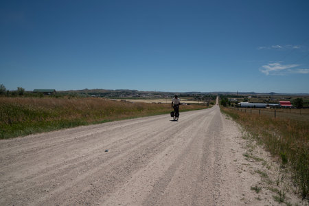 Cyclist riding on a dirt road in the countryside in summerの写真素材