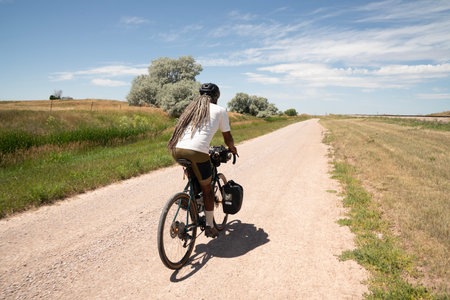 Rear view of a man riding a bicycle on a country roadの写真素材