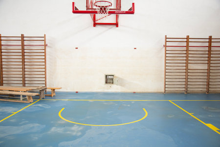 Interior of a gymnasium with basketball hoop and seats.の写真素材