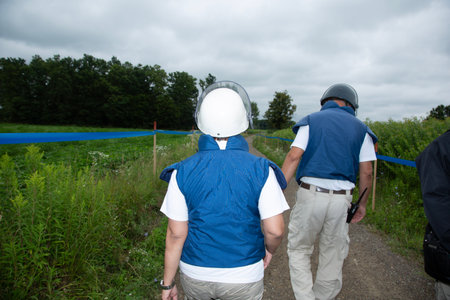 Rear view of two men holding hands while walking in the fieldの写真素材