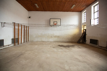 Interior of an old abandoned building with a basketball hoop in the foregroundの写真素材