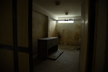 interior of an old prison cell in a dark room with a windowの写真素材