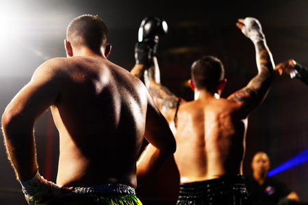 Two professional boxers fighting in ring at night. Focus on foregroundの写真素材