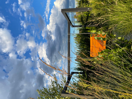 Orange structure with glass panel and chain on blue sky backgroundの写真素材