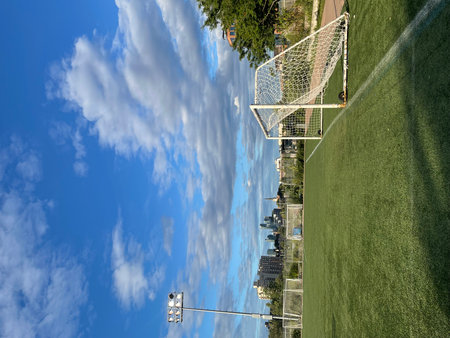 Soccer field with green grass and blue sky with white clouds.の写真素材