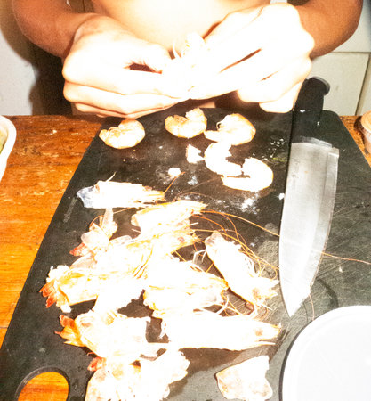 cooking shrimps on a black cutting board with a knifeの写真素材