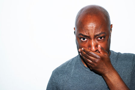 African american man covering his mouth and looking at the camera.の写真素材