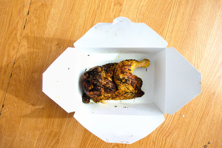 roasted chicken in a white box on a wooden table, top viewの写真素材