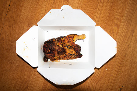 Roast chicken in a white cardboard box on a wooden background.の写真素材
