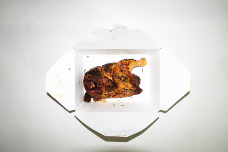 Roasted chicken in a cardboard box on a white background, top viewの写真素材
