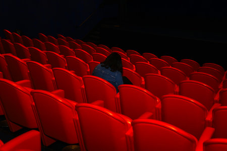 Rear view of a woman sitting in a red cinema auditoriumの写真素材