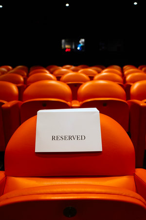 Rows of orange chairs with reserved sign in cinema hall, stock photo