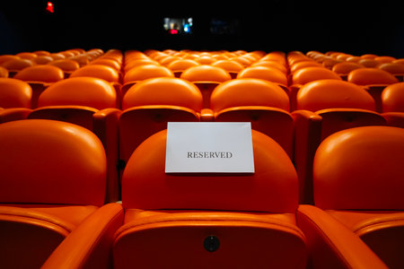 Rows of orange seats in the auditorium with a reserved seatの写真素材