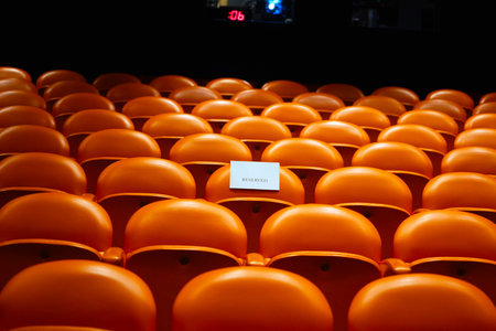 Orange plastic seats in the stadium with a sign.の写真素材