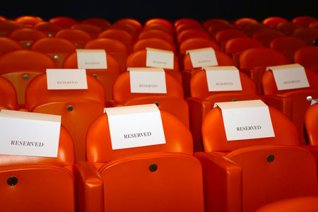 Empty red seats in an auditorium with a lot of paper notesの写真素材