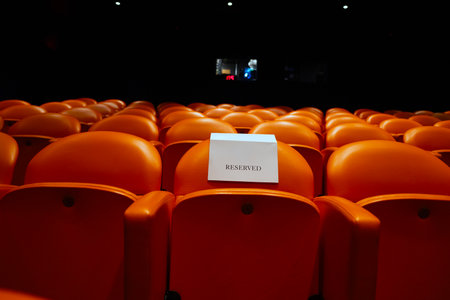 Empty orange chairs in a cinema hall with a blank white signの写真素材
