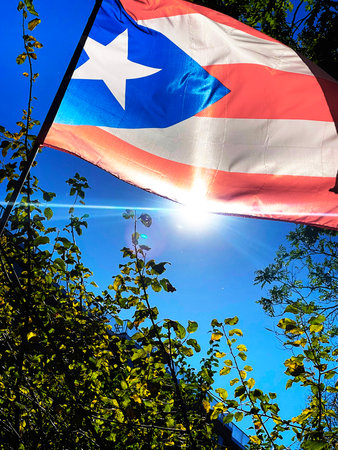National flag of Puerto Rico against the blue sky with the sun.の写真素材
