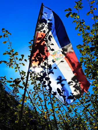 Flag waving in the wind against the blue sky and the sunの写真素材