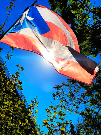 Flag waving in the wind against the blue sky and sunの写真素材