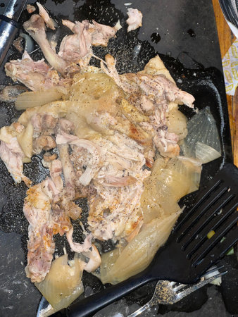 Chicken on a black frying pan, close-up.の写真素材