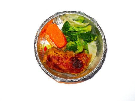 roast chicken with vegetables in a foil box on a white backgroundの写真素材