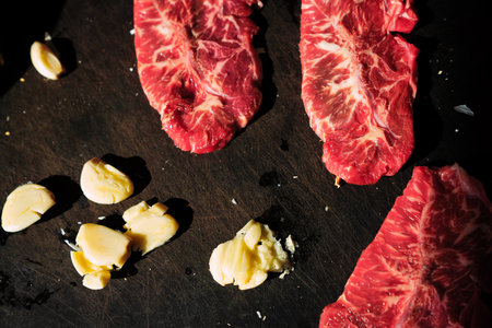 raw beef steak with garlic and butter on a black background. tinting. selective focusの写真素材