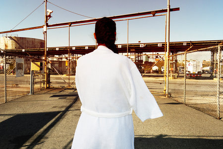 Back view of a young woman in a white bathrobe standing on an abandoned factory.の写真素材