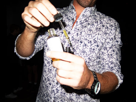 man in a shirt with a bottle of alcohol on a black backgroundの写真素材