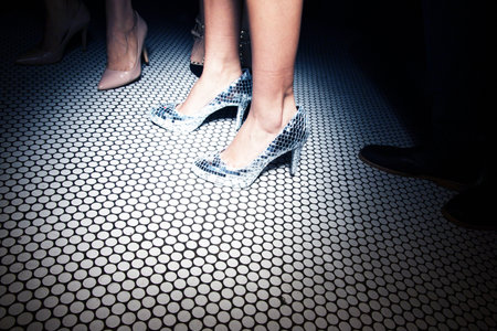 Closeup of female legs in high heel shoes on a floor.