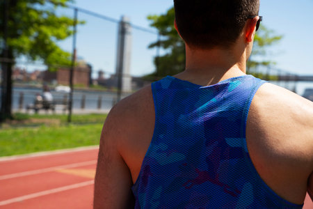 Rear view of a man standing on a track and field during a sunny day