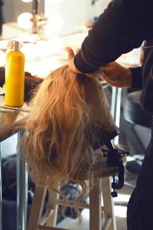 Hairdresser combing blond hair in a beauty salon.の写真素材