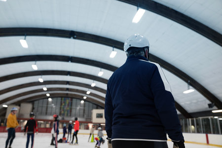 Rear view of man with ice hockey helmet looking at skating rink