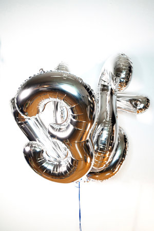 Silver foil balloon in the form of the number 18 on a white backgroundの写真素材