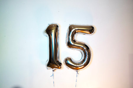Number 15 gold foil balloon on white background. Anniversary, birthday, celebration.の写真素材