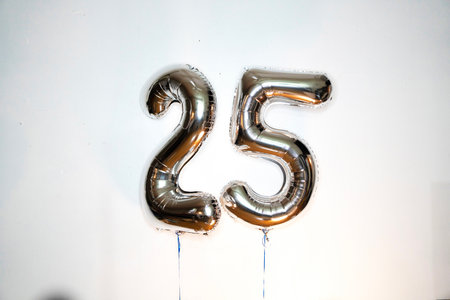 Number 25 gold foil balloon on a white background, closeup of photoの写真素材