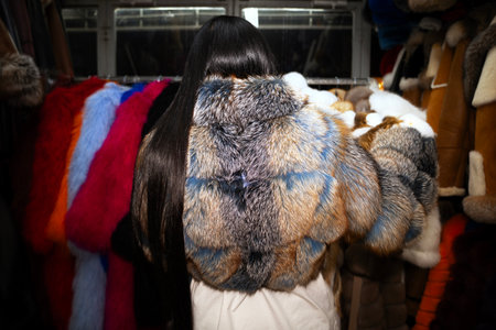 Rear view of a young woman wearing a fur coat in a shop