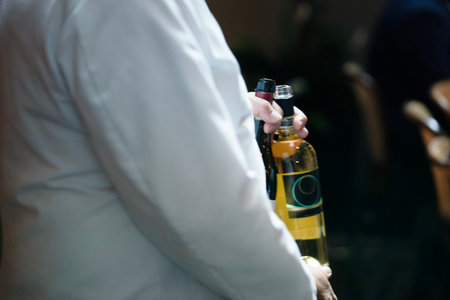 Waiter holding a bottle of white wine, focus on the bottleの写真素材