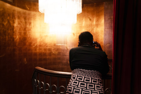 Rear view of african american woman using mobile phone at home