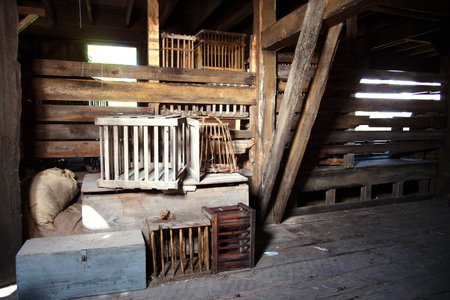 Interior of a wooden house with a cage in the foreground.