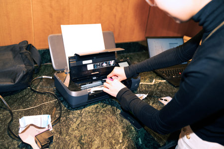 Close-up of a woman's hands holding a credit card and using a laser printer.