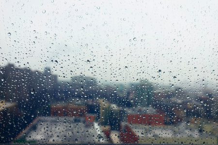 Rain drops on the window with a view of the city and buildings