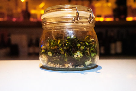 Glass jar filled with dried contents on the white table.