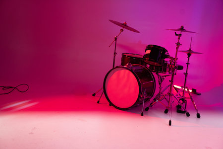 Drum kit on a pink background in neon light. Percussion musical instrument.