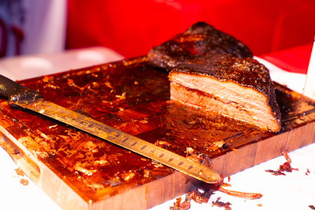 Smoked meat on a wooden board with a knife and a thermometer