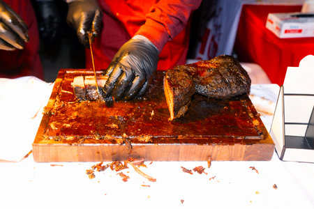 Barbecued meat on a wooden board in the hands of a cook