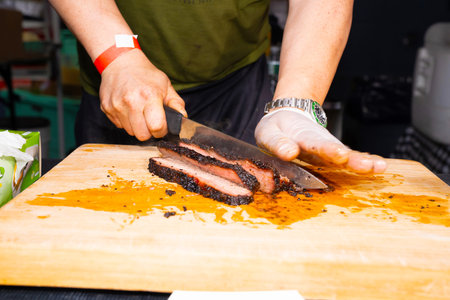 Chef cutting beef steak on a wooden cutting board in a restaurant kitchen
