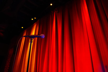 Microphone on stage with red curtain background, close up view.