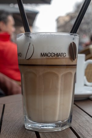 a glass of latte macchiato standing on a table in a street cafeの写真素材