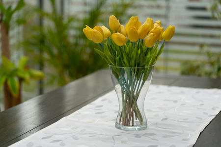 a vase with yellow tulips is on the tableの写真素材